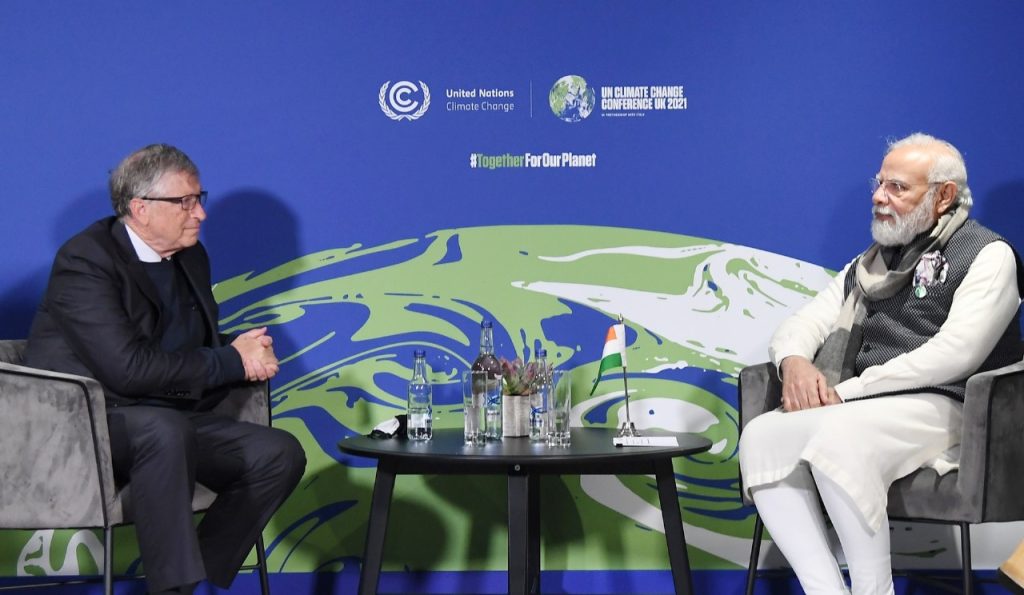“Two leaders sitting across from each other during the UN Climate Change Conference UK 2021, discussing global climate issues with conference branding in the background.”
